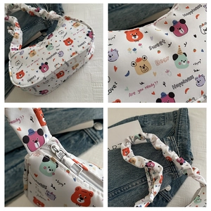 Detail view of cartoon bear print and pleated shoulder strap on white underarm bag
