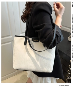 Détail du grand sac cabas blanc avec anses noires et étiquette FASHION porté