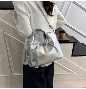 Close-up of silver metallic bucket bag featuring delicate white lace bow details