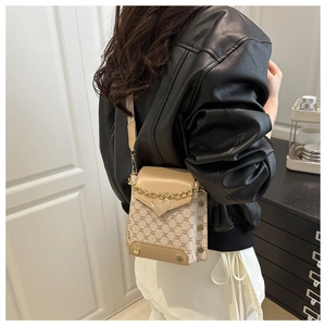 Détail d'un mini sac carré beige avec boucle en cœur et bandoulière en chaîne dorée