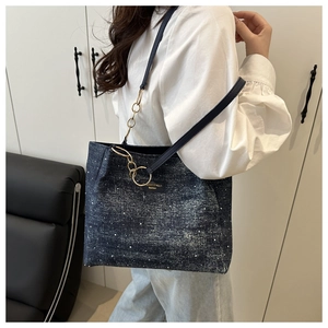 Detail of blue denim tote bag with white polka dots, featuring a brand logo leather patch