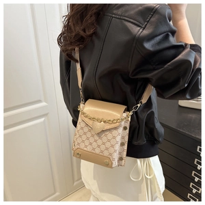 Détails d'un sac bandoulière beige avec fermoir cœur et motif monogramme vintage