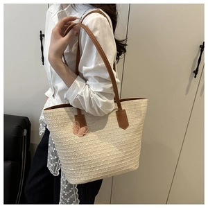 Détail de la texture d'un sac cabas en paille avec papillon rose et anse en cuir