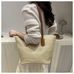 Straw tote bag with pink flower detail and brown leather straps shown on model