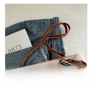 Detail of beige nylon tote bag with brown leather straps and plush bear charm accessory