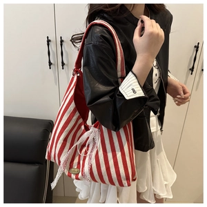 Detail of red striped canvas tote bag featuring lace bow and handmade metal plate