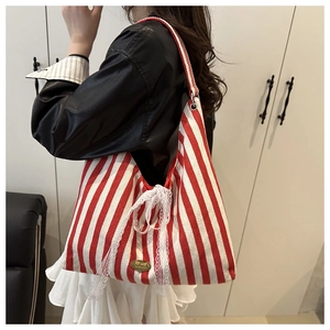 Detail of red and white striped canvas tote bag with lace bow and handmade metal tag