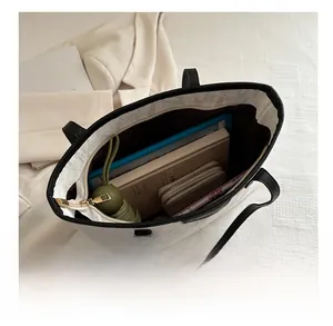 Detail view of large white tote bag interior holding a folding umbrella, tablet, and wallet