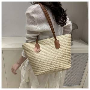Close-up of straw beach tote featuring leather straps and pink lace bow charm