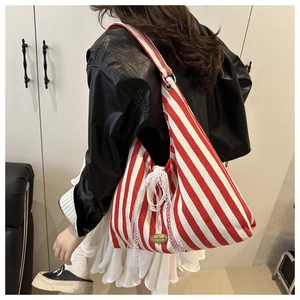 Detail of red striped canvas tote bag with a white lace bow and handmade metal plate