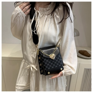 Détail du sac bandoulière carré avec motif vintage, chaîne dorée et sangle en nylon