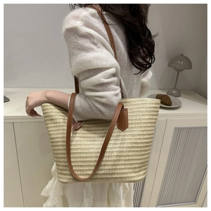 Gros plan d'un sac cabas en paille tressée avec anse en cuir et breloque papillon