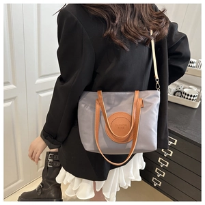 Waterproof nylon tote bag with leather straps shown as a stylish crossbody on a model