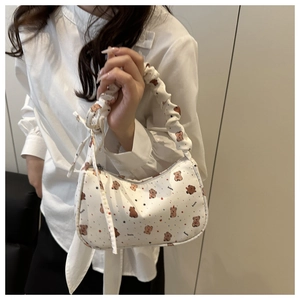 Detail of white canvas shoulder bag featuring brown cartoon bear print and ruched handle