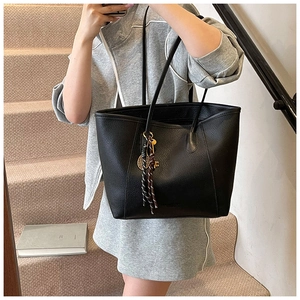 Close-up of black lychee grain leather tote bag with tassel and key pendant details