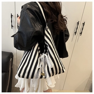 Detail view of canvas tote bag featuring black and white stripes with a lace bow
