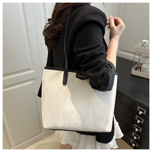 Détail d'un grand sac cabas blanc à texture froissée et poignées en cuir noir de haute qualité