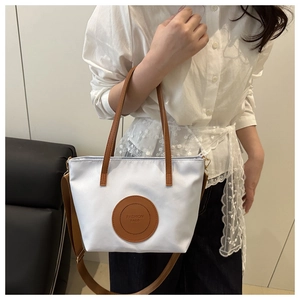 Detail of nylon tote bag with leather straps and circular Fashion Bags logo patch
