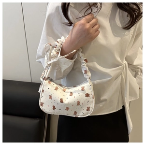 Detail of white baguette bag with cartoon bear prints and ruffled handle on model