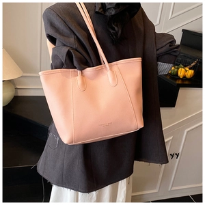 Pink bucket bag with lychee texture and thin strap shown on a model in a home setting