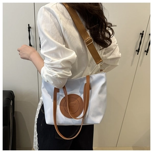 Side view of model wearing a light blue contrast tote bag with brown woven strap