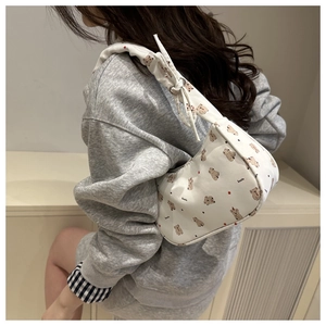 Close-up of a white canvas shoulder bag with brown koala print and ruffled strap detail