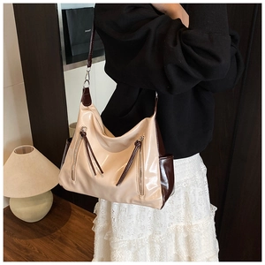 Macro shot of large beige patent leather shoulder bag with zipper and tassel details