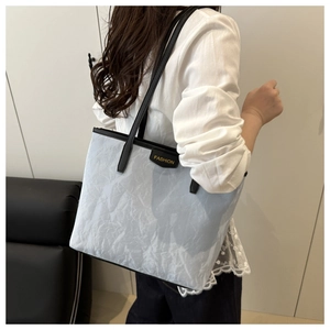 Detail of light blue marble texture tote bag with black strap and fashion label
