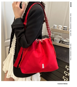 Vue détaillée du sac cabas en toile rouge avec cordon et bandoulière à carreaux sur modèle
