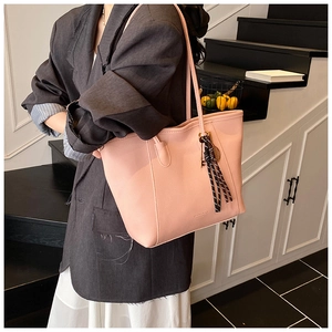 Detailed view of pink lychee leather tote bag with woven pendant and brand logo