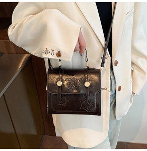 Detail der dunkelbraunen quadratischen Tasche mit goldenen Sternen und Ledergriff