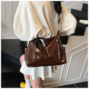 Detail of dark brown patent leather tote bag with stylish vertical metal zippers