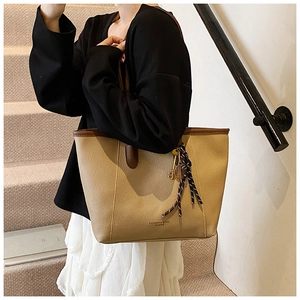 Detail of khaki pebbled leather tote bag with silk scarf and gold racket charm detail