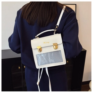 Close-up of white square backpack featuring a gold metal lock and grid mesh window detail