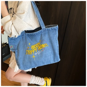 Detail der blauen Denim-Tragetasche mit gelber 3D-Stickerei und Retro-Regenbogen-Motiv