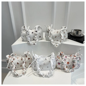 Detail of five pleated underarm bags with cartoon bear and letter prints on white steps