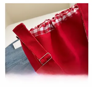 Détail de la boucle en métal réglable et du tissu en toile rouge de la bandoulière