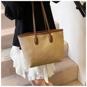 Close-up of the large khaki tote bag with brown leather straps and minimal text