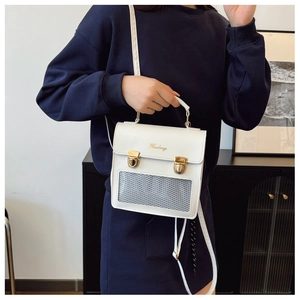 White mini crossbody bag with gold clasps and grey mesh pocket detail worn by a model
