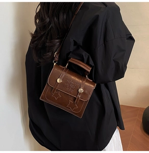 Details einer braunen Ledertasche mit Sternprägung und goldenem Verschluss im Retro-Stil