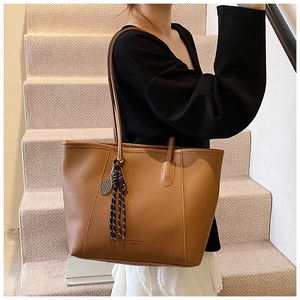 Macro detail of the caramel brown lychee leather texture and the side braided pendant accessory