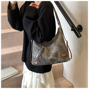 Detail der grauen Retro-Hobo-Tasche mit braunem Lederband und Reißverschluss-Deko