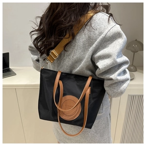 Detail view of model wearing a nylon tote bag with contrasting wide shoulder strap