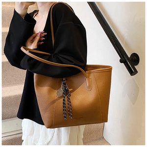 Close-up of caramel lychee grain leather tote bag with unique tennis racket pendant