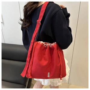 Détail du sac seau en toile rouge avec fermeture à cordon à carreaux et logo fashion