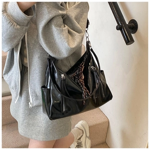 Detail of black glossy patent leather shoulder bag with silk scarf on a staircase