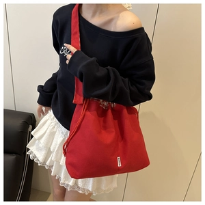 Détail d'un sac cabas en toile rouge avec cordon de serrage et étiquette de mode devant