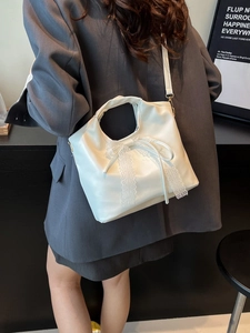 White faux leather tote bag with lace bow detail and adjustable crossbody strap