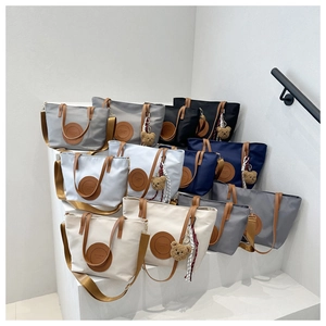 Waterproof nylon tote bags in various colors displayed with plush bear charms and straps