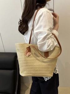 Natural straw tote bag with brown straps and pink lace butterfly charm for beach vacations